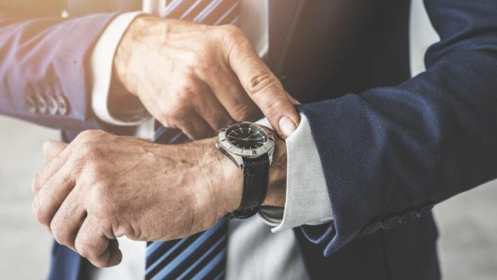 Geschäftsmann schaut auf seine Uhr und sucht nach mehr Zeit für Führung